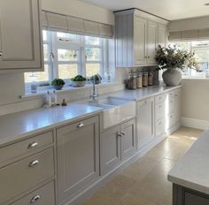 a kitchen with white cabinets and marble counter tops