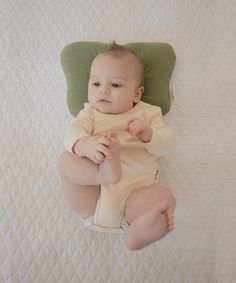 a baby laying on top of a green pillow