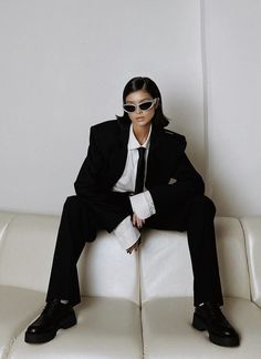 a man in a suit and sunglasses sitting on a white couch