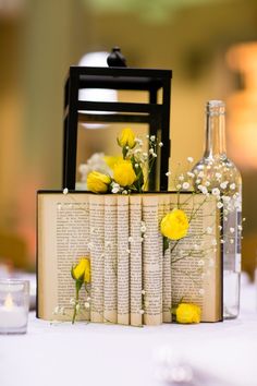 an open book with yellow flowers on it sitting next to a vase filled with baby's breath