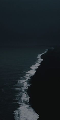 a black and white photo of the ocean at night