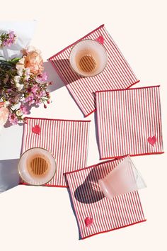 three red and white striped placemats next to a vase with flowers on it