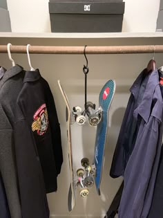 there is a skateboard and other items on the shelf in this closet, along with t - shirts