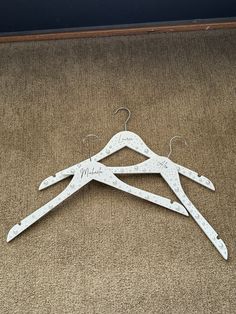 three white wooden clothes hangers with names on them