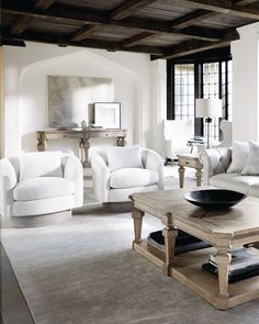 a living room filled with white furniture and lots of wood beams on the ceiling,