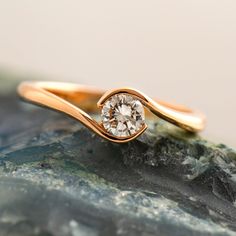 a gold ring with a diamond in the middle on top of a rock next to some rocks