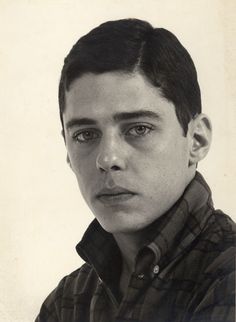 a black and white photo of a young man with short hair wearing a button up shirt