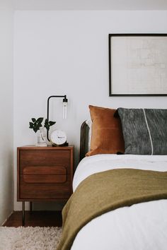 a bed room with a neatly made bed and a night stand on top of it