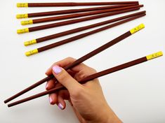 a person holding chopsticks in their hand with yellow labels on them that read 1 - 3 / 4