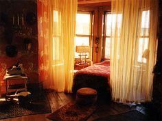 a bedroom with wooden floors and curtains on the windows