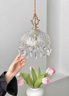 a chandelier hanging from the ceiling over a vase with tulips