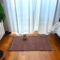 a brown rug sitting on top of a wooden floor next to a potted plant