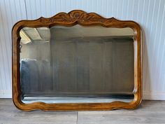 a large mirror sitting on top of a hard wood floor next to a white wall