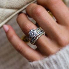 a woman's hand with three different rings on her finger and one ring in the other