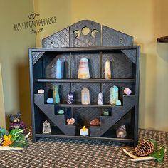 a wooden shelf with candles and rocks on it sitting on a table next to a pine cone