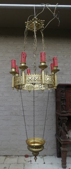 a chandelier hanging from the ceiling in front of a white brick wall with red candles