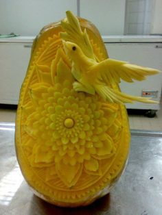 a yellow bird sitting on top of an orange flower carved into it's shell