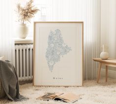 a framed map is sitting on the floor next to a blanket and chair in front of a radiator