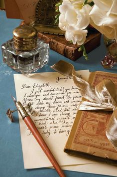 an old fashioned pen, inkwell and paper on a blue tablecloth with flowers