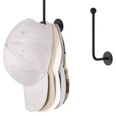 a baseball cap and hat hanger on a white wall with black metal hooks