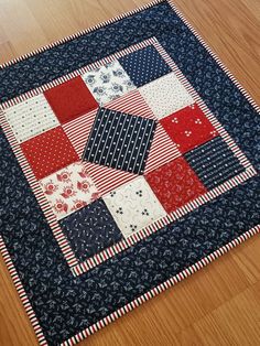 a close up of a patchwork quilt on a wooden floor