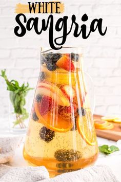 a pitcher filled with fruit sitting on top of a table next to a white brick wall