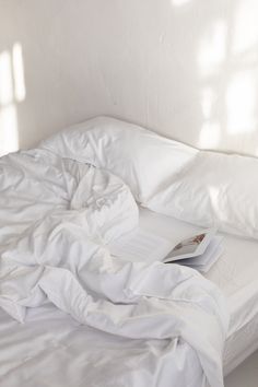 an unmade bed with white sheets and pillows