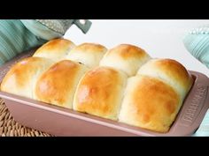 six rolls in a baking pan on a wicker basket next to some blue dishes