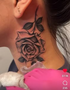 a woman's neck with a rose tattoo on her left side behind the ear