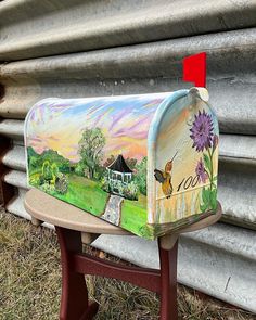 a painted mailbox sitting on top of a wooden bench