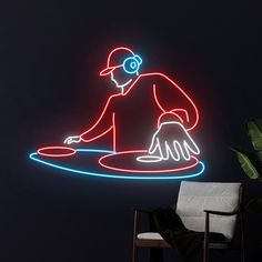 a man sitting in front of a neon sign with headphones on his ears, using a laptop