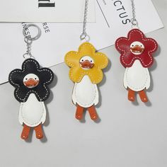 three keychains with different designs on them, one has a flower and the other has a bird