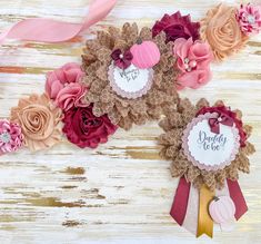 some pink and brown flowers are on a white wooden surface with ribbons around them that say daddy to be