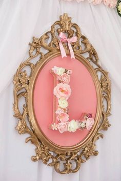 the letter j is decorated with pink flowers and ribbons in an ornate gold framed frame