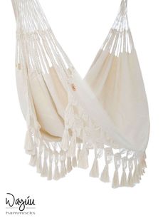 a white hammock with tassels hanging from it's back end