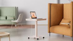 an open laptop computer sitting on top of a white table next to a yellow chair