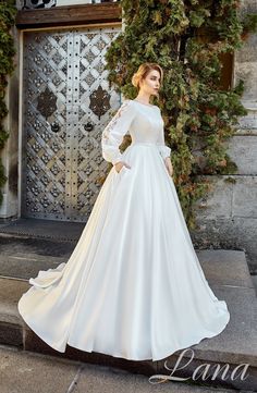 a woman in a white wedding dress standing on steps with her hands on her hips