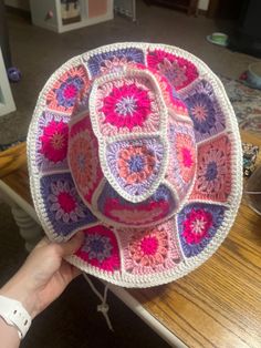 someone is holding up a crocheted dishcloth on a table in the living room