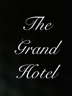 the grand hotel sign is lit up in the night sky with white writing on it