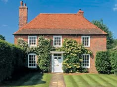 a large brick house with white windows and ivy growing on it's side wall