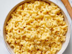 a white bowl filled with macaroni and cheese on top of a marble counter