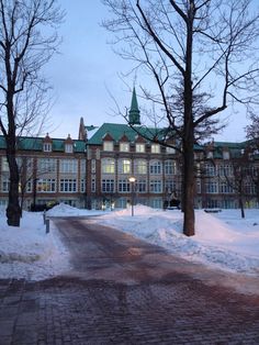 a large building that is next to some trees with snow on the ground in front of it