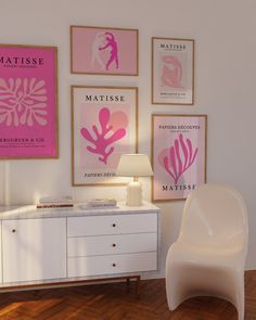 a white chair sitting next to a table in front of a wall with posters on it