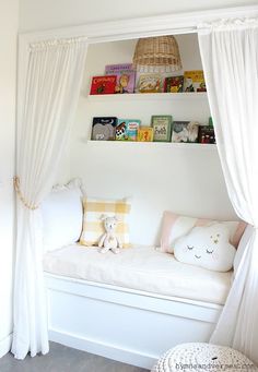 a white day bed sitting under a window next to a book shelf filled with books