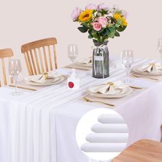 a table set with place settings and flowers in a vase