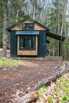 a small wooden cabin in the woods surrounded by trees and fallen leaves on the ground