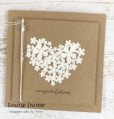 a brown card with white flowers in the shape of a heart