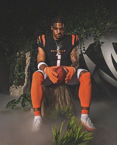 a man sitting on top of a tree stump holding a football