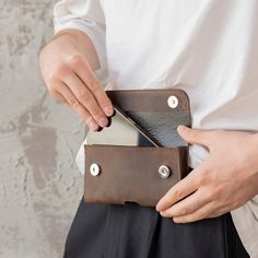 a person holding a wallet in their left hand and an electronic device in the other