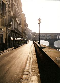 an empty street with buildings and a lamp post in the distance, on a sunny day